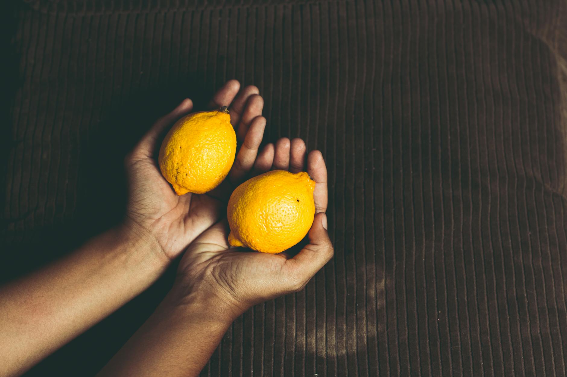 Close-up of two fresh lemons held in cupped hands, symbolizing reconnection and renewal