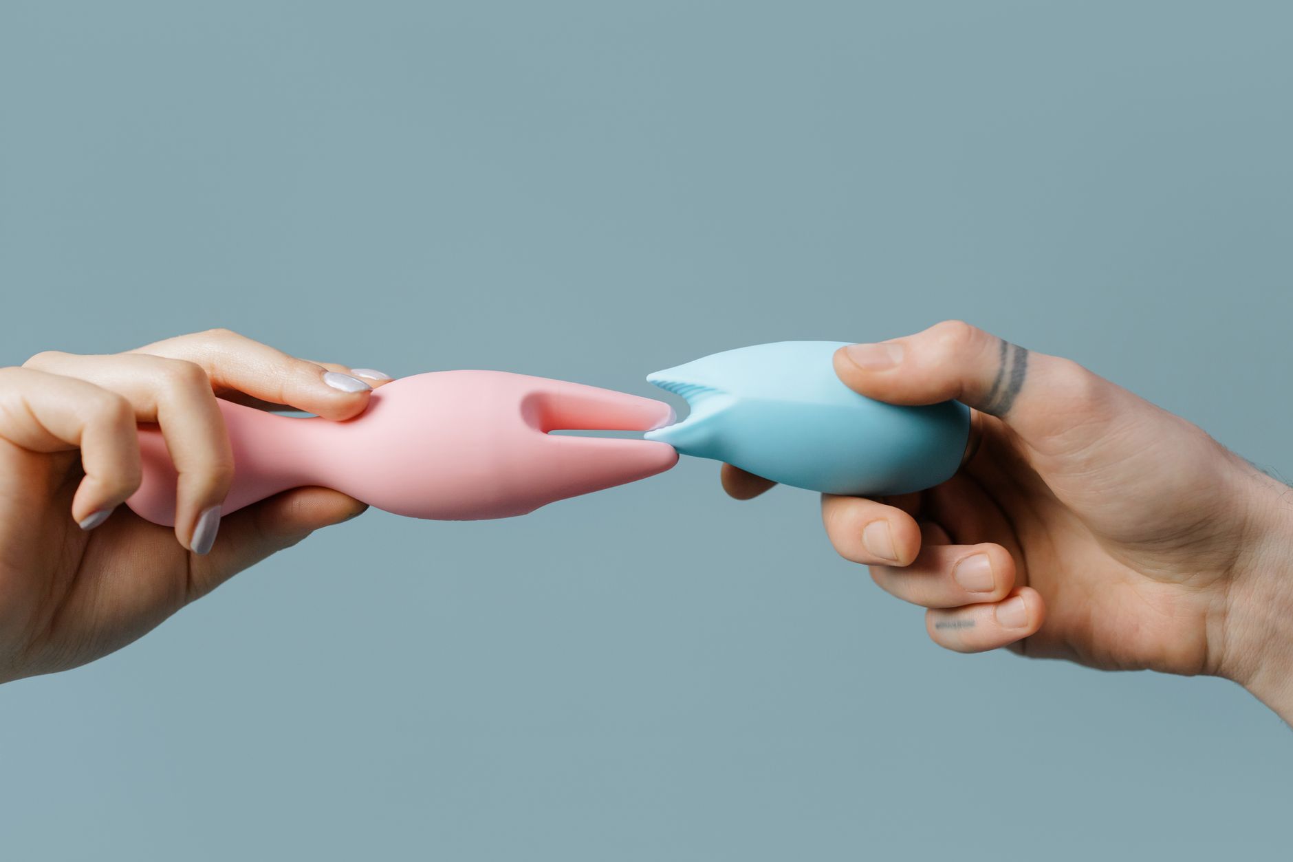 Close-up of hands holding a sleek clitoral vibrator against a purple background