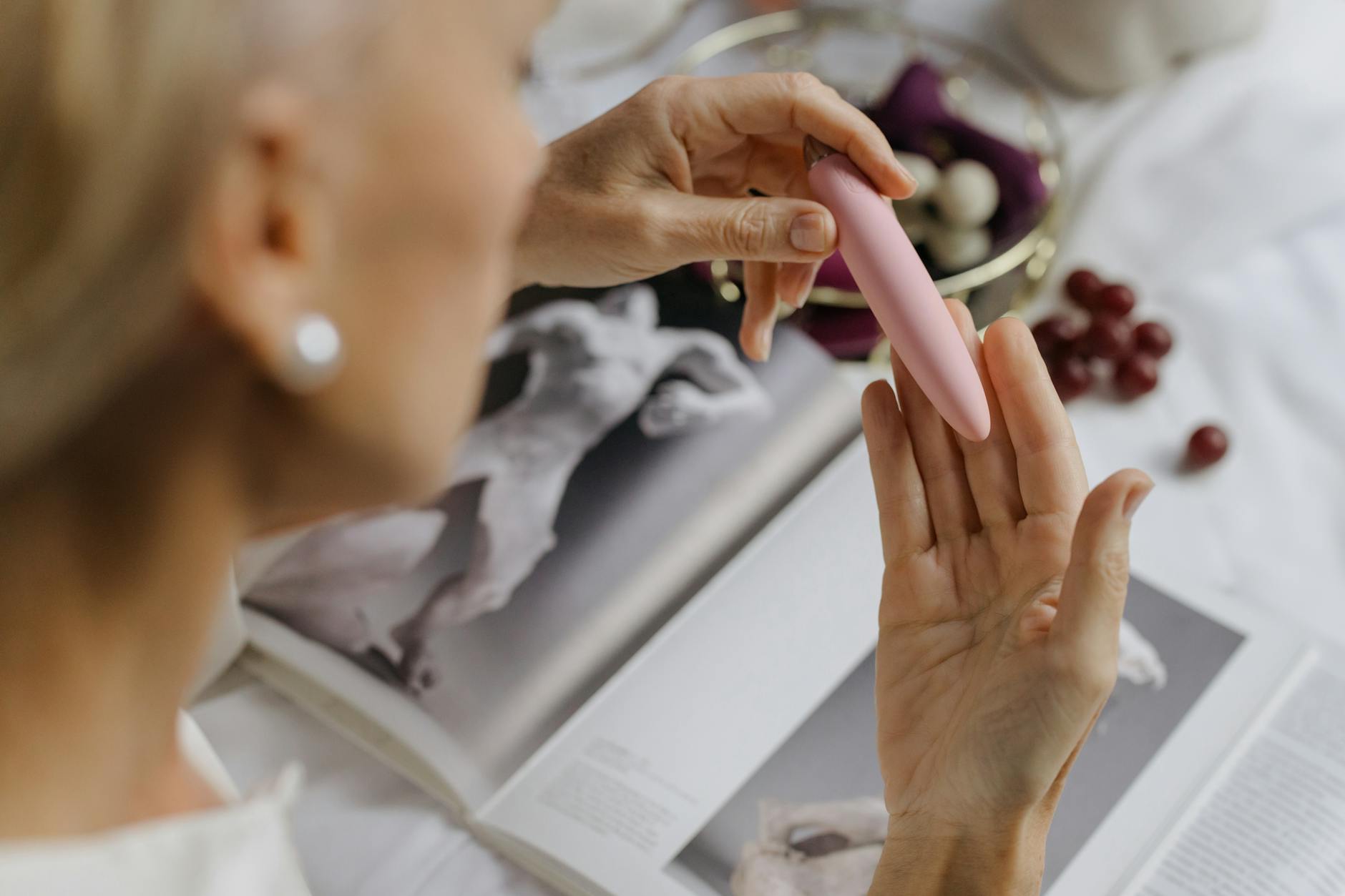 Person thoughtfully holding blue and pink silicone vibrators, representing intimate rediscovery in long-term relationships