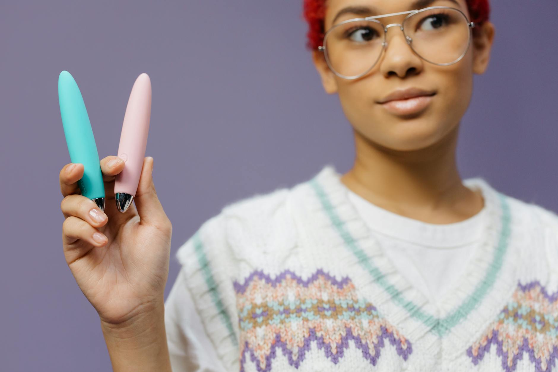 Woman holding colorful vibrators and adult toys against a purple background