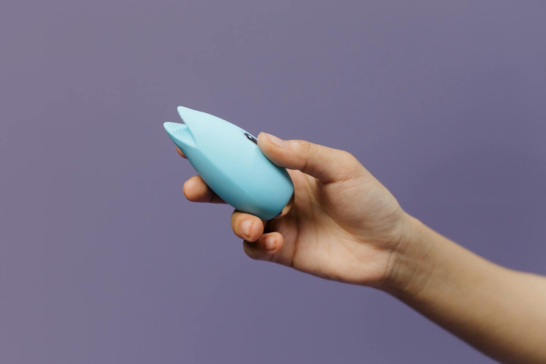 A blue silicone vibrator held in hand, symbolizing intentional pleasure and connection