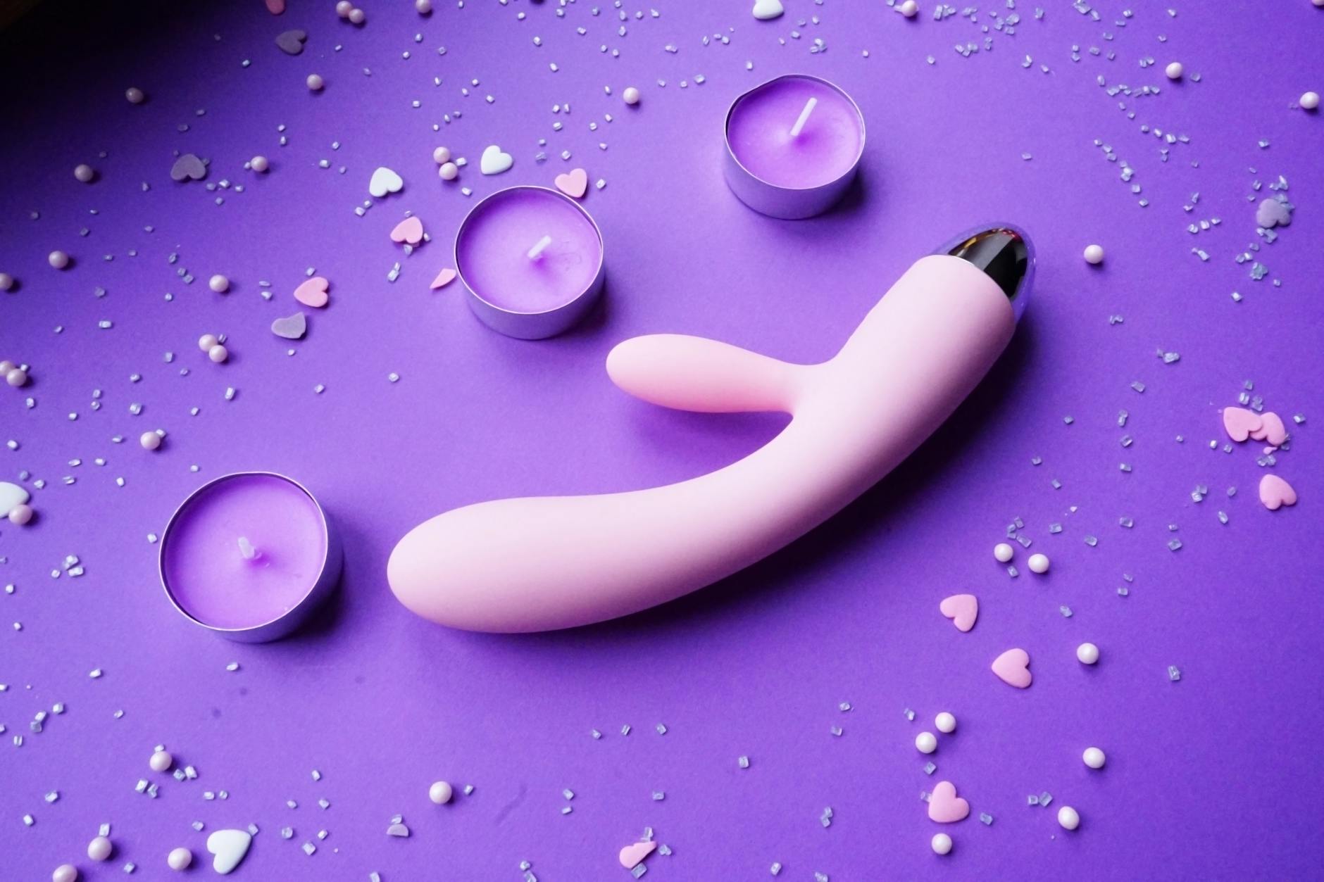 A hand holding a vibrator against a purple backdrop, showcasing body-safe toy design