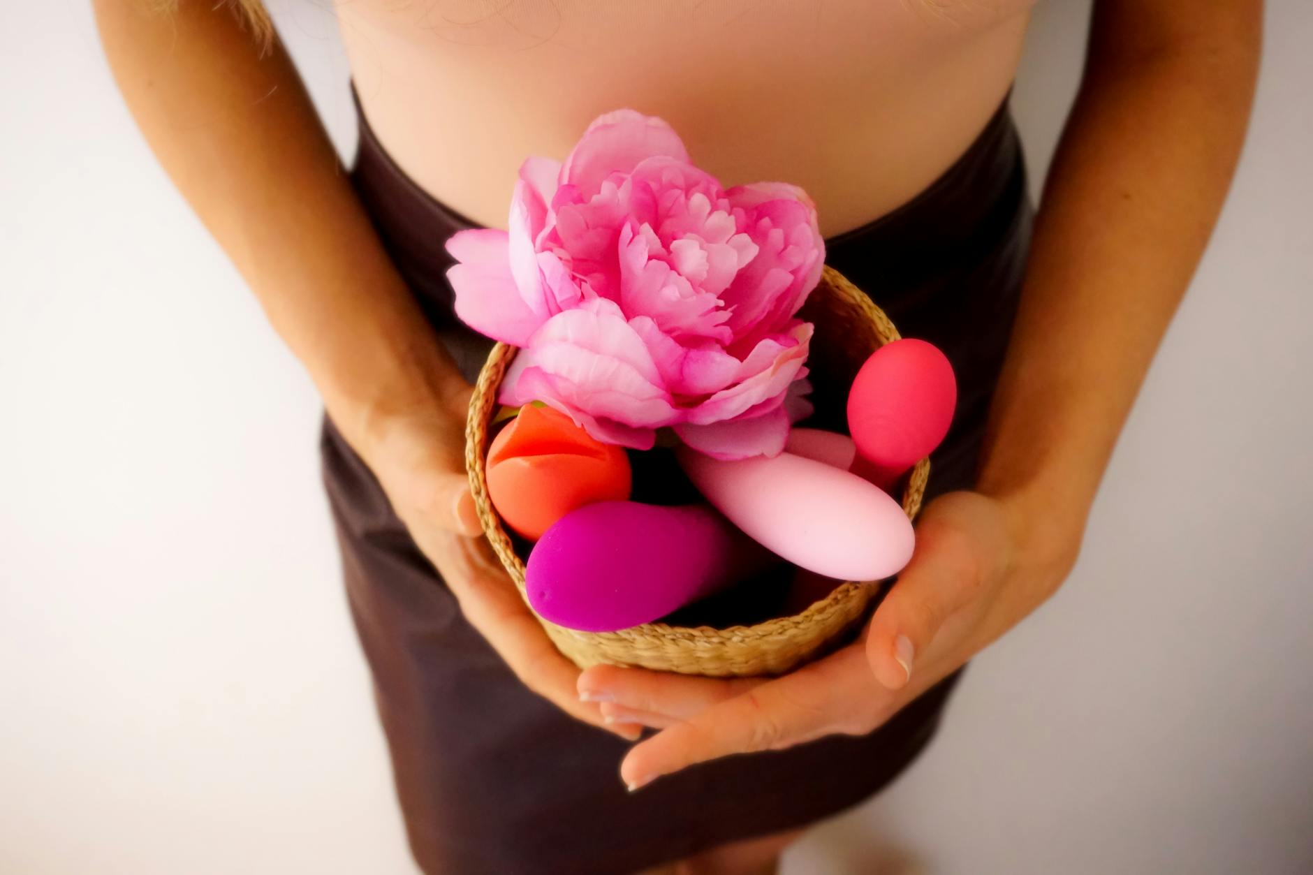 Hands holding pastel-colored silicone vibrators in contemplative exploration