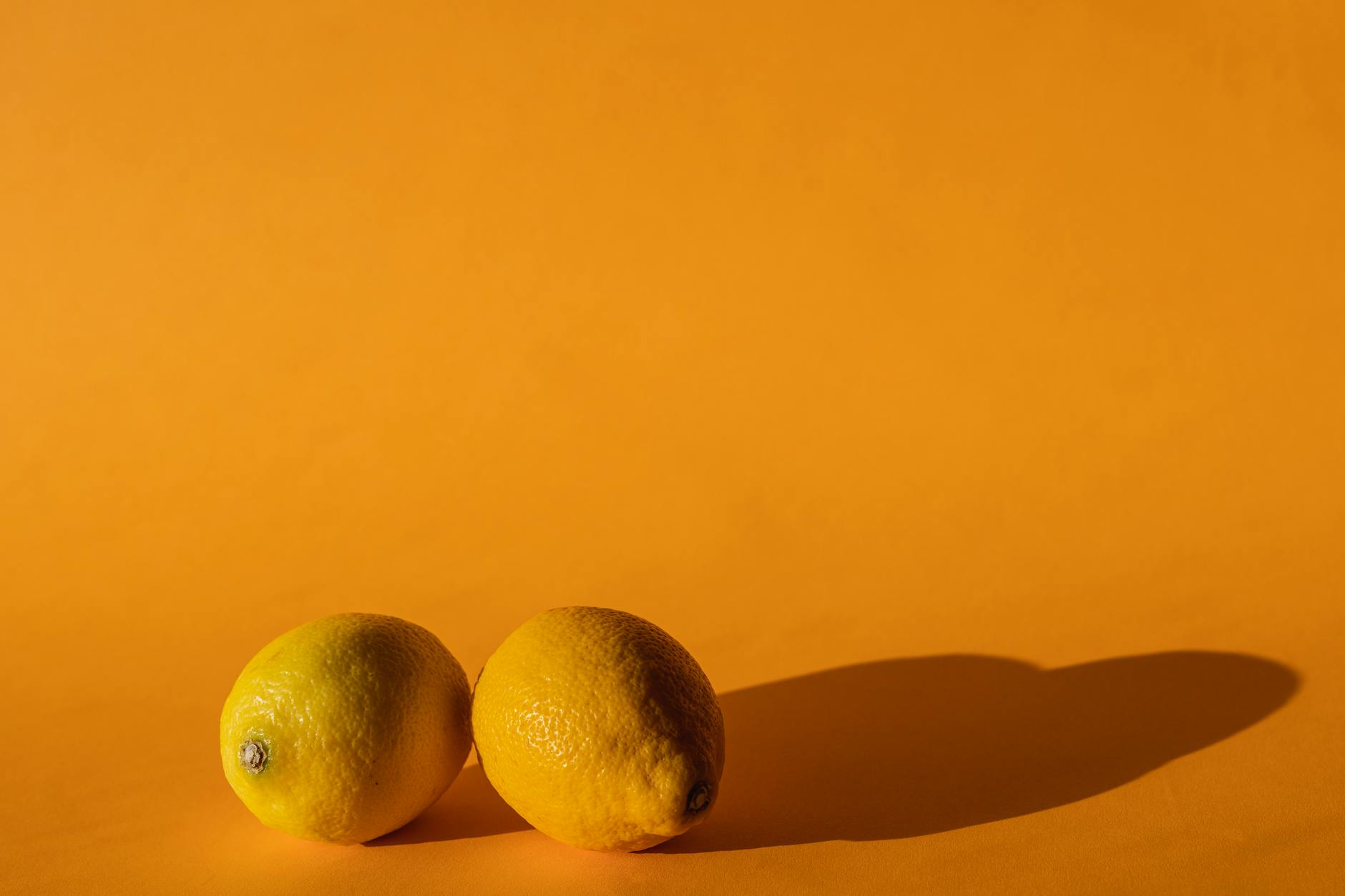 A close-up of a hand holding an orange vibrator against a minimalistic purple backdrop, showcasing modern sensuality.
